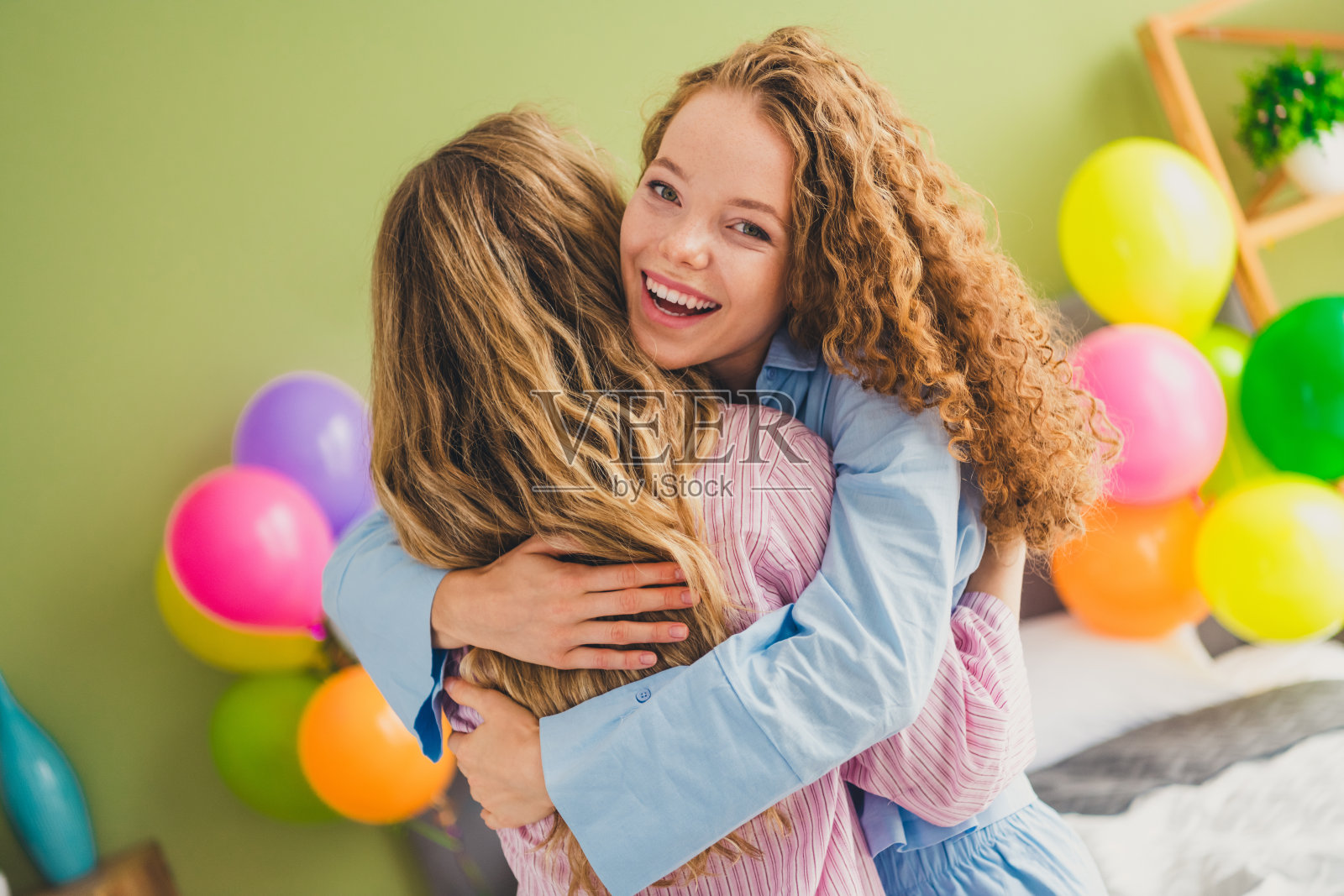 两位可爱的小女孩在现代舒适明亮的卧室里拥抱,穿着愉快的睡衣,享受刚醒来的时光。照片摄影图片