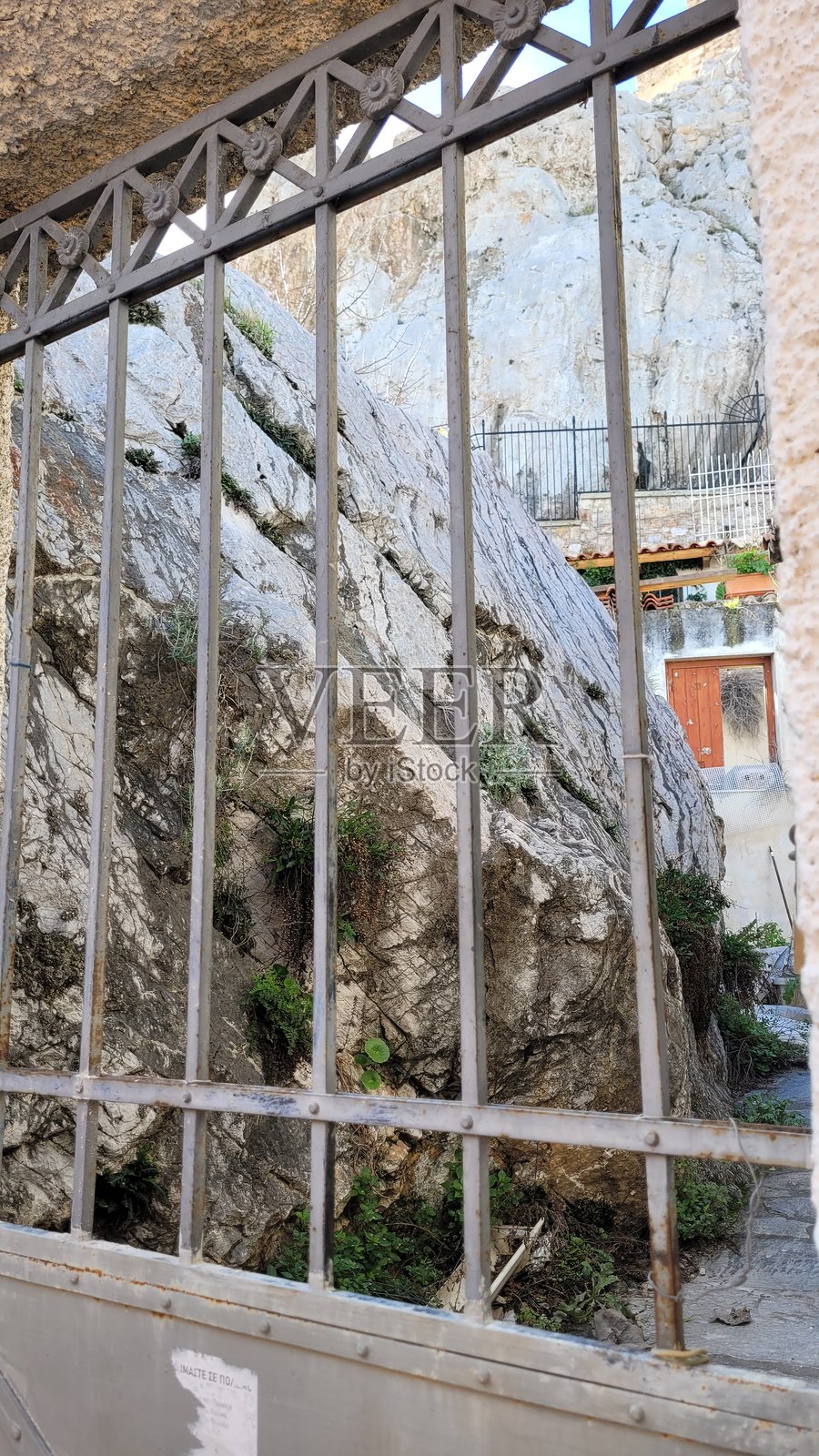 在照片中,一个巨大的石头透过金属格栅可见。照片摄影图片