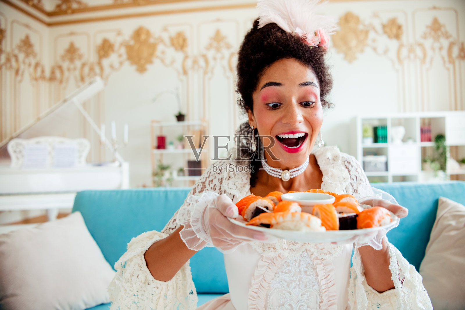 年轻女性穿着优雅的复古服装,兴奋地在室内端着寿司拼盘照片摄影图片
