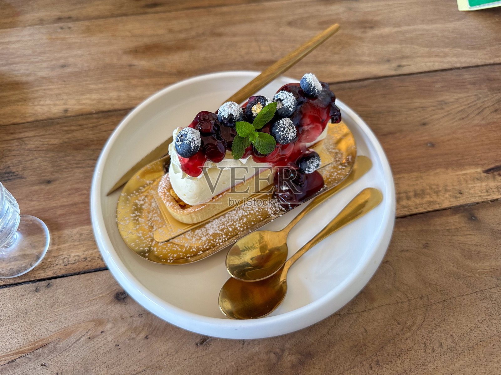 美味的浆果甜点,由新鲜的奶酪蛋糕和蛋糕组成,装饰着红色草莓和蓝莓。照片摄影图片