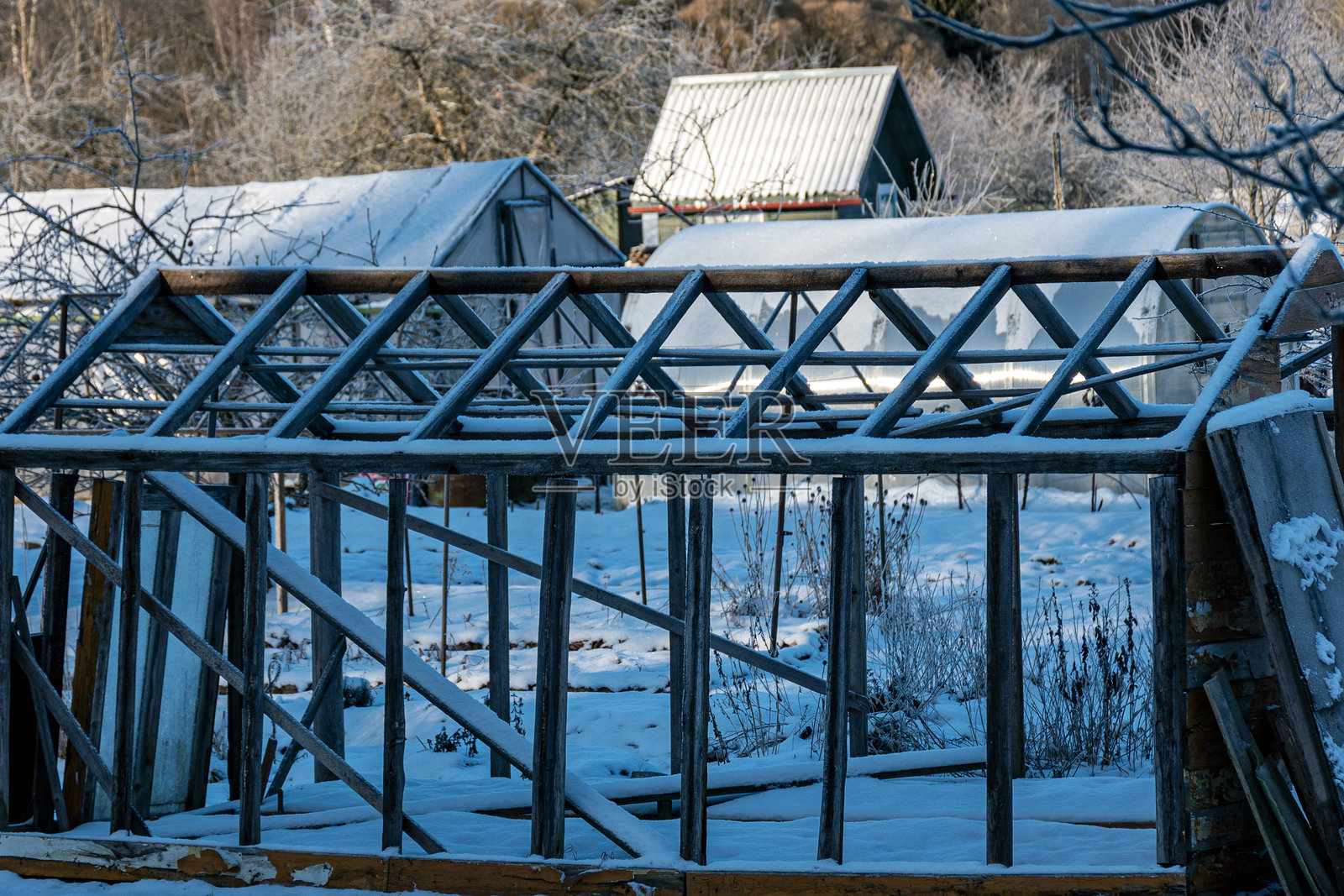 美妙的冬日,树木和草地覆盖着霜冻,花园里有一座破旧的老电影温室。照片摄影图片