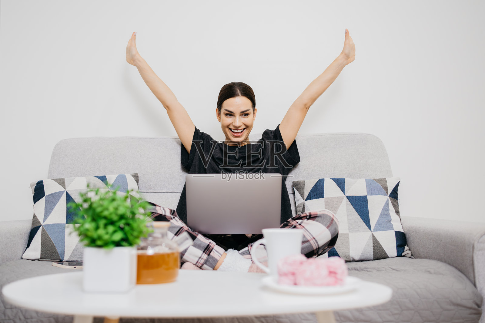 一位快乐的女性在笔记本电脑前庆祝收到令人兴奋的消息,对一个新机会感到兴奋。照片摄影图片