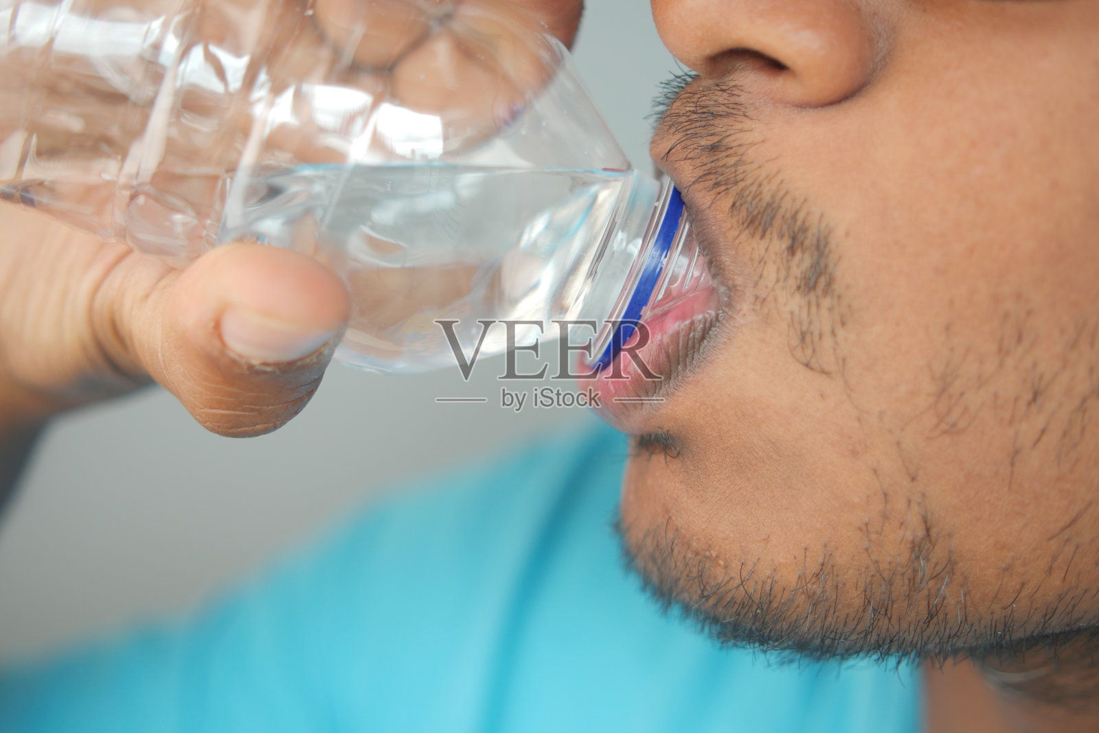 一个人在休闲环境中直接从瓶子里喝水的特写图像照片摄影图片