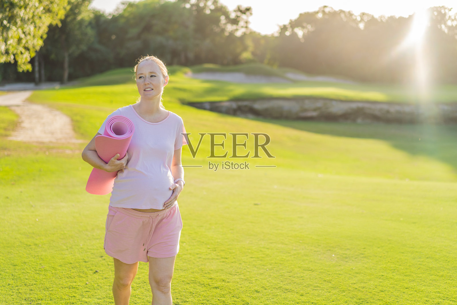 充满活力的孕妇在户外锻炼,使用瑜伽垫进行清新健康的户外运动。照片摄影图片