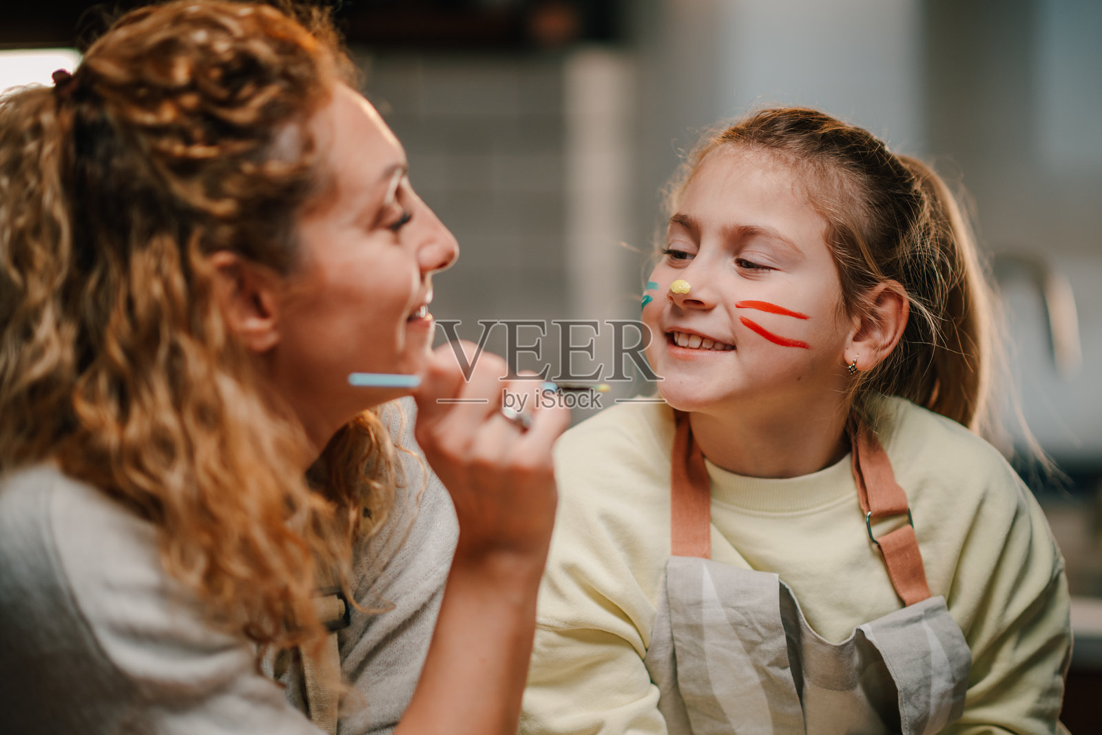 母亲在家给女儿画脸,享受快乐时光照片摄影图片