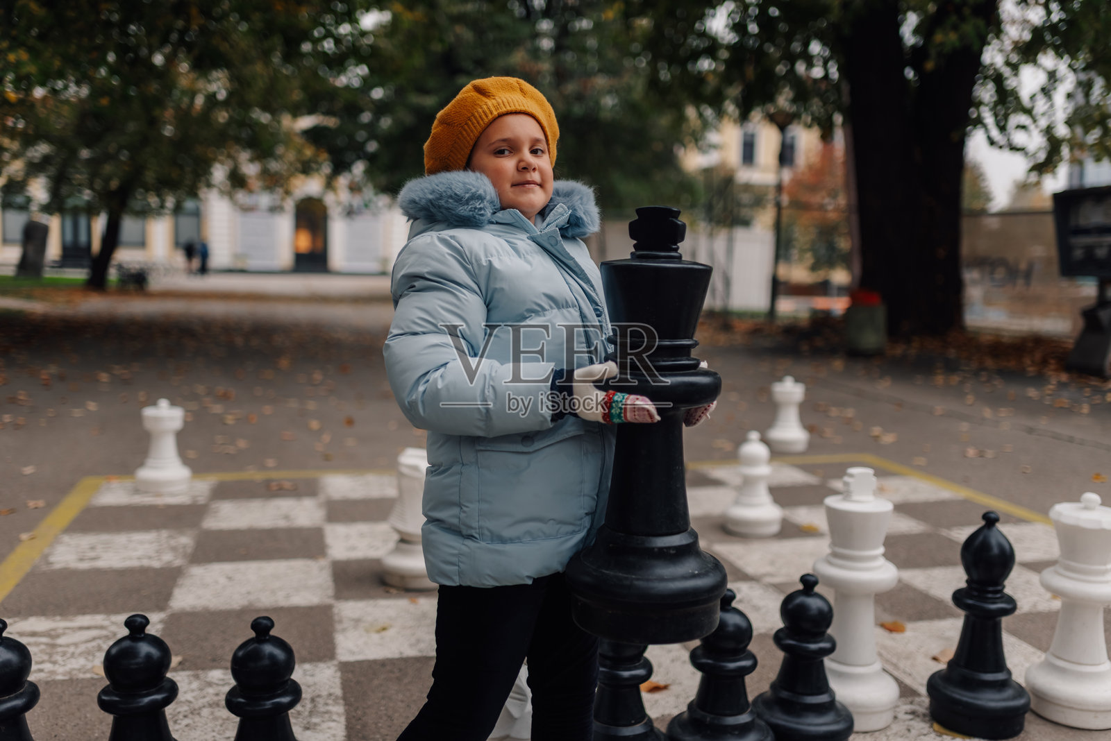 女孩在秋天的公园里玩巨型国际象棋照片摄影图片