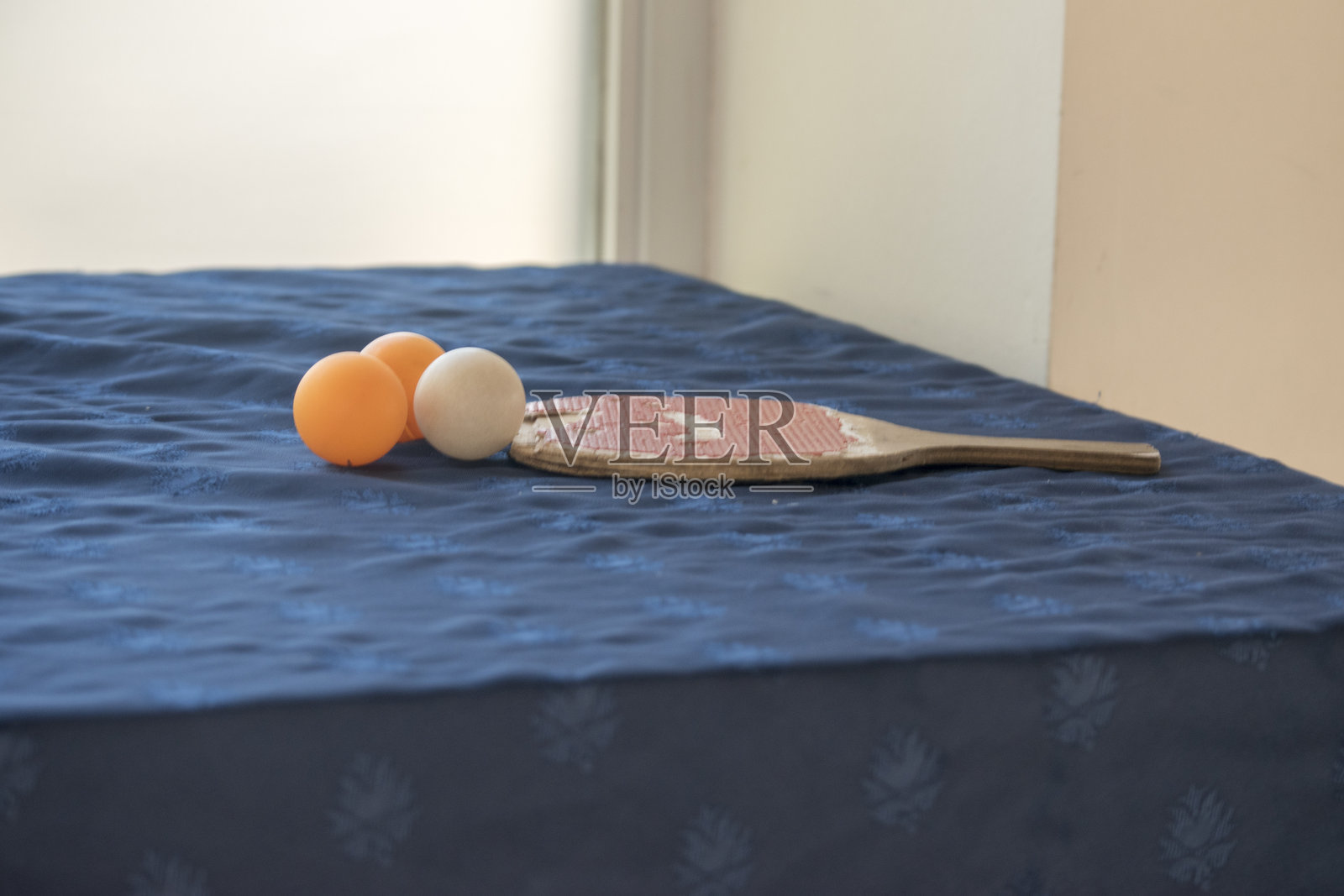 蓝色桌子上的乒乓球拍和三个球照片摄影图片