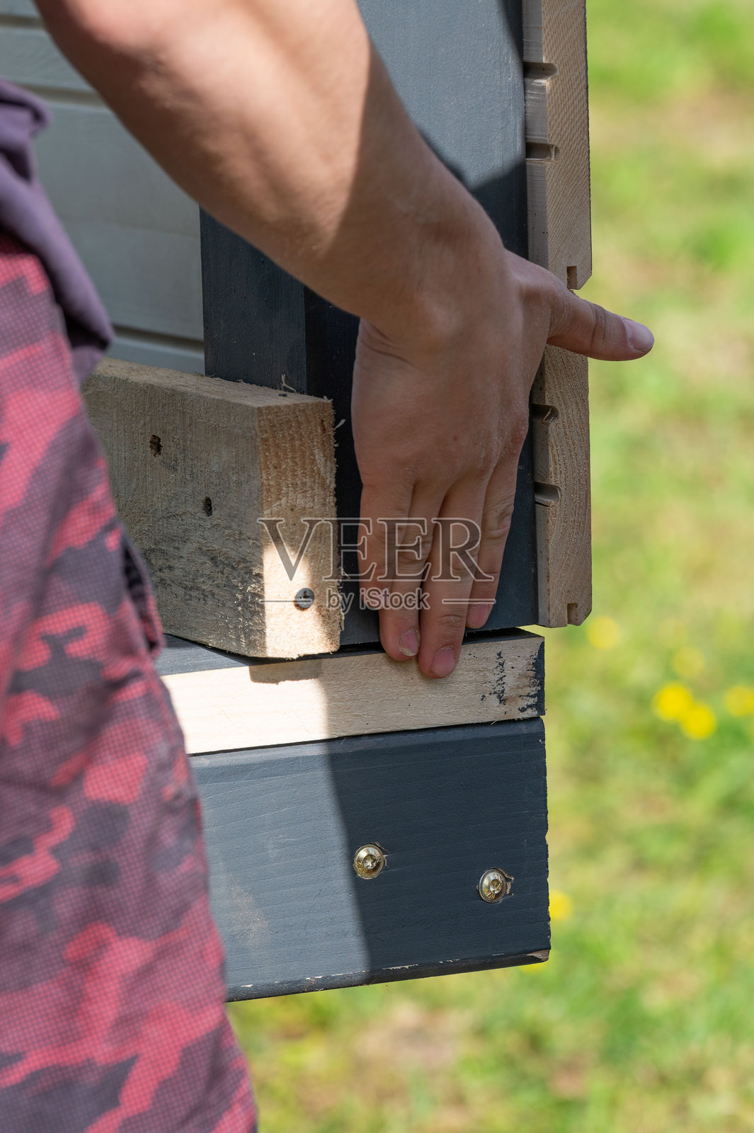 一名工人在安装凉亭时,用手支撑墙边以与地面进行比较。照片摄影图片