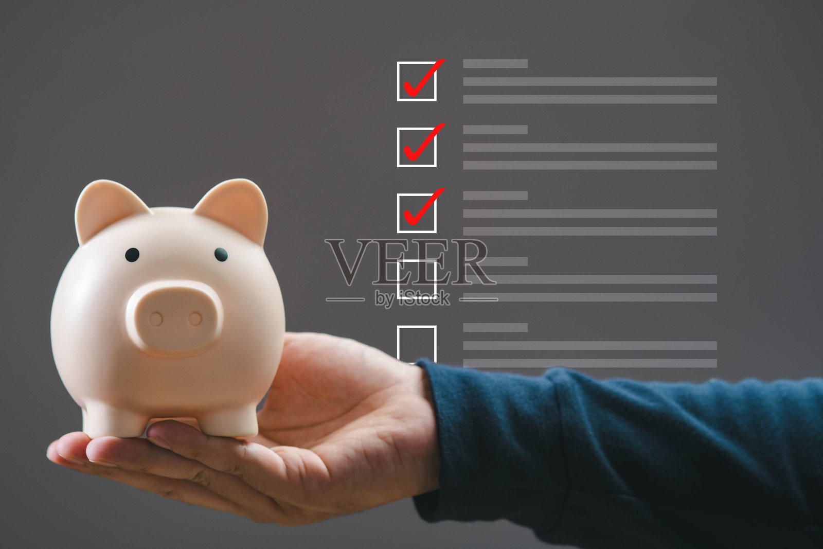 一个人手持一个存钱罐,背景中有已完成的任务,象征着财务规划和目标实现。非常适合财务主题。照片摄影图片