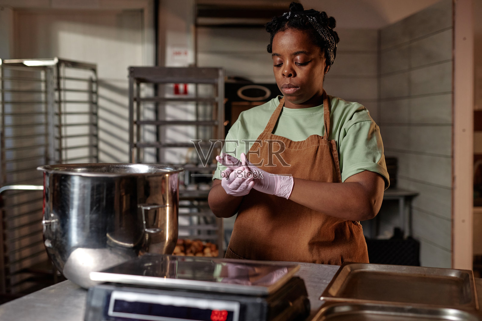 成年黑人女性厨师在面包店厨房中揉面团制作饼干照片摄影图片