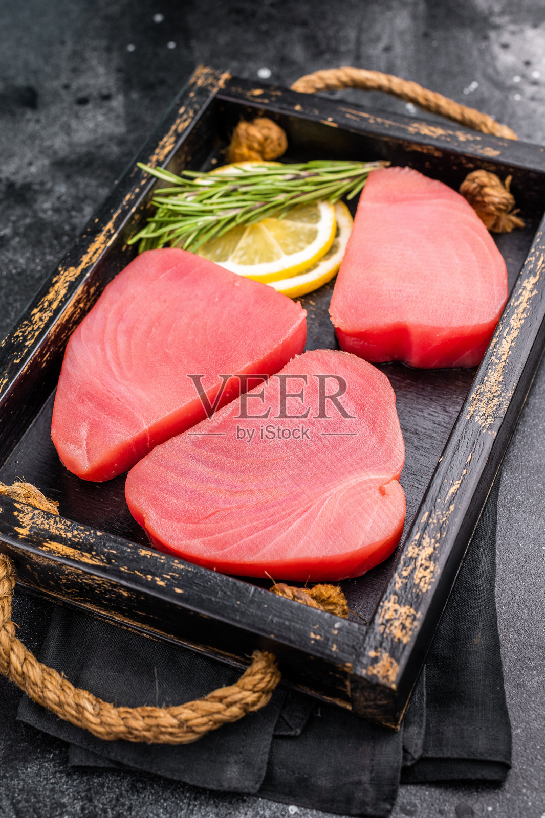 新鲜切片的生金枪鱼里脊,富含风味和营养,等待被制作成精致的海鲜菜肴。黑色背景。俯视图。照片摄影图片