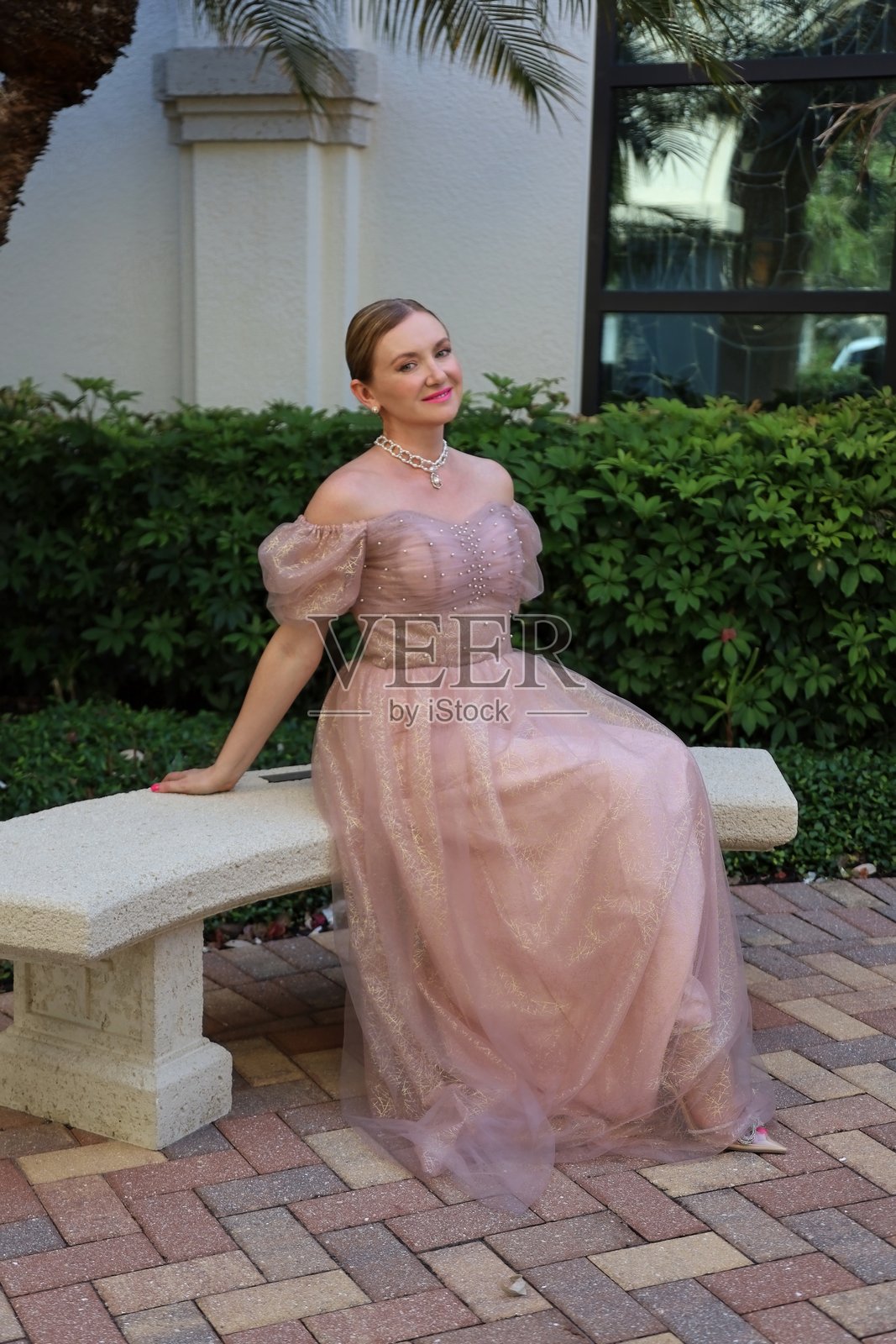 年轻模特穿着晚礼服,粉色裙子外罩透明紫色层。照片摄影图片