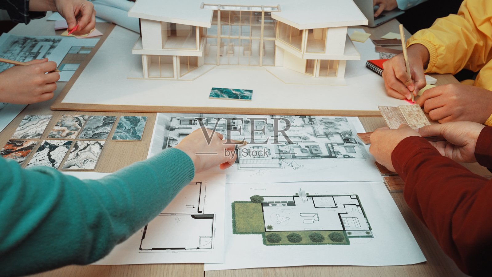 现代建筑项目的协作设计会议,桌面上展示了比例模型和详细计划照片摄影图片