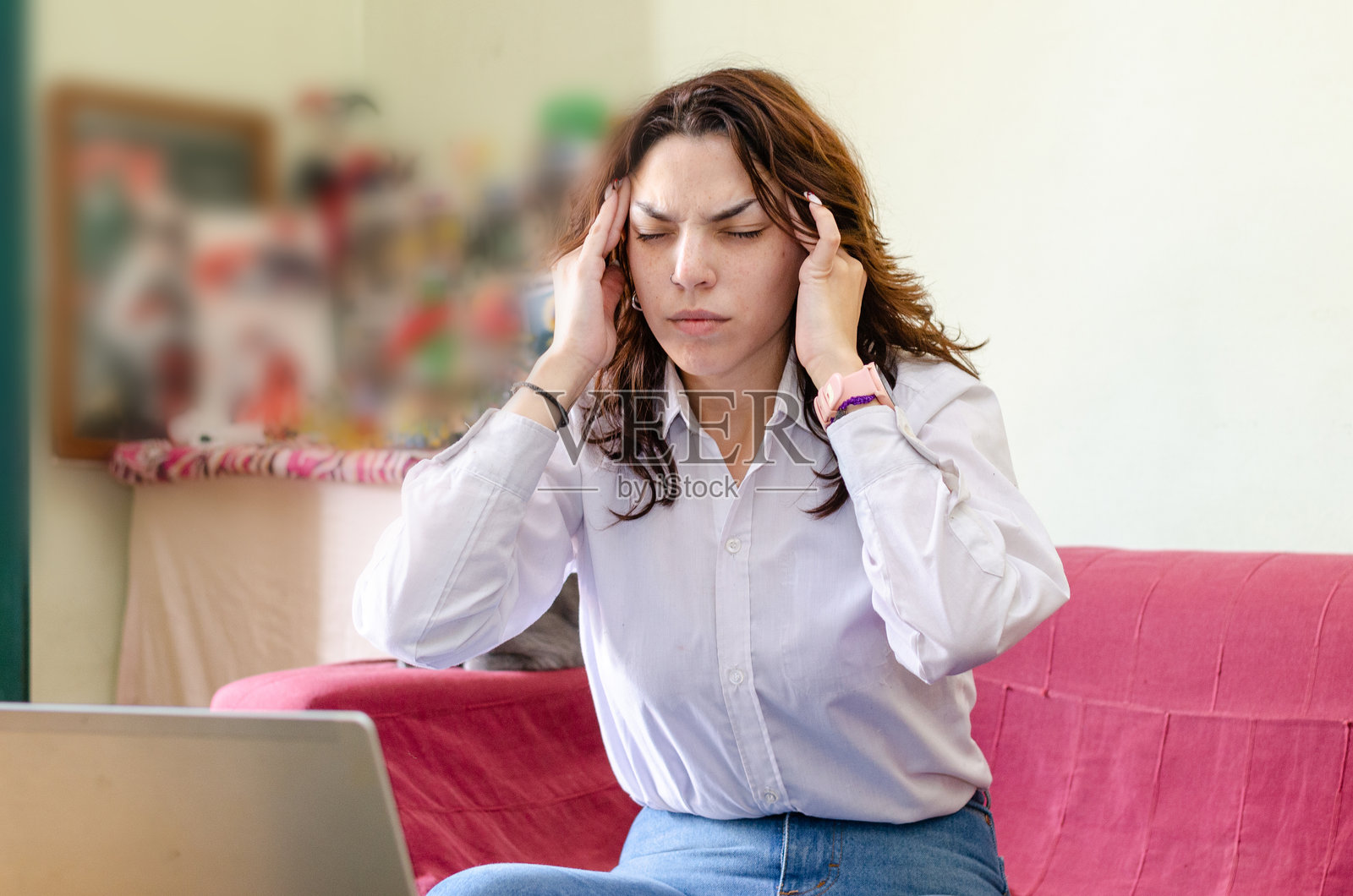 年轻女性员工在家用笔记本电脑工作,因偏头痛而捂住头部。照片摄影图片