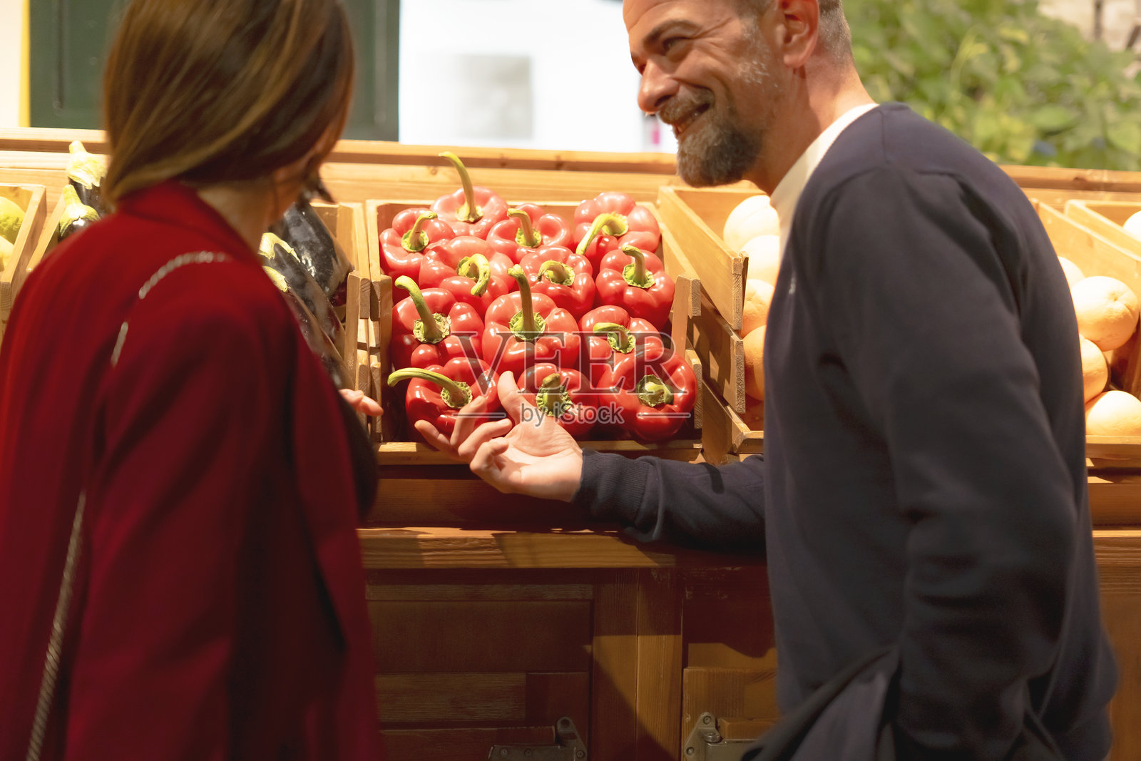 杂货店的水果蔬菜商向顾客展示红椒照片摄影图片