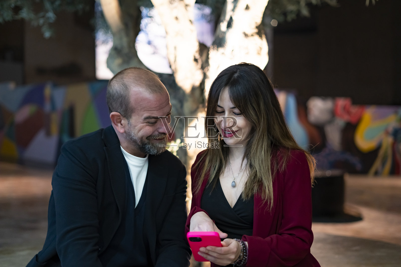 商务人士在夜晚的橄榄树下共享智能手机照片摄影图片