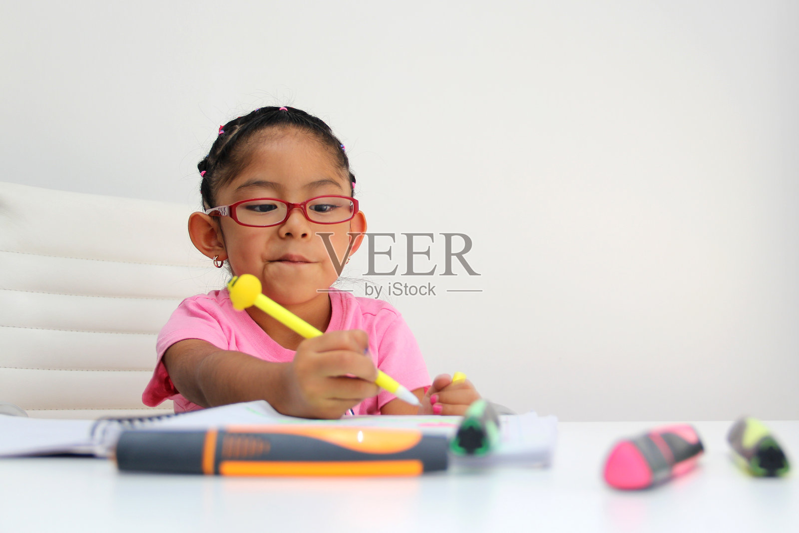 4岁拉丁裔女孩,患有自闭症谱系障碍(ASD),如阿斯伯格综合症、雷特综合症和海勒综合症,独自在桌子上画画,玩颜色,表现出反社会倾向。照片摄影图片