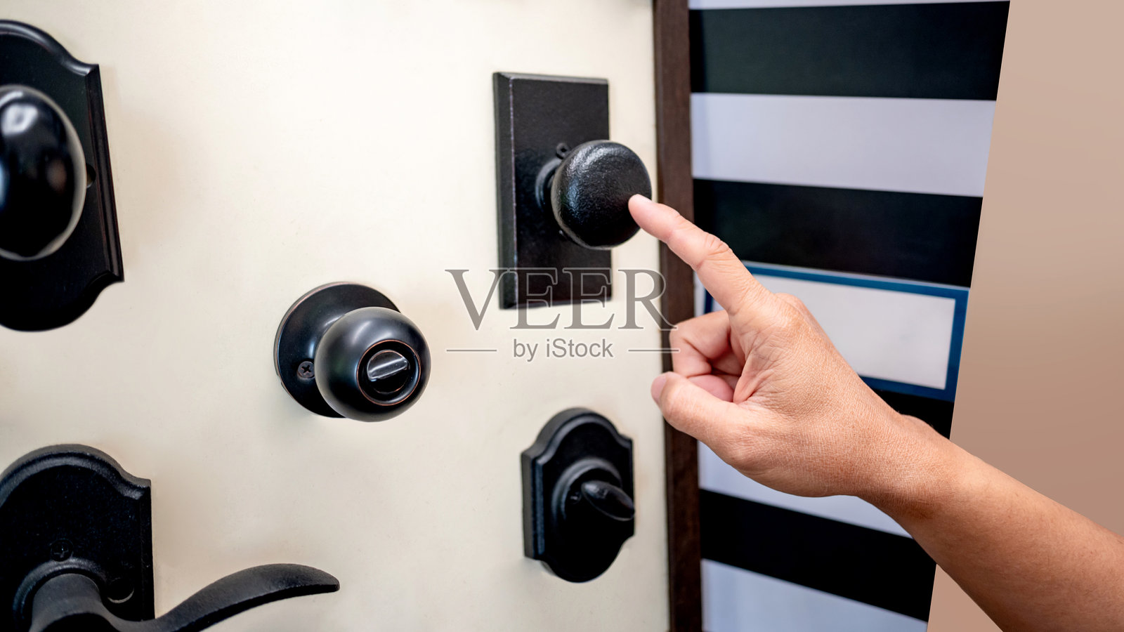 设计师手指向五金店样品收藏中的复古实心门把手照片摄影图片