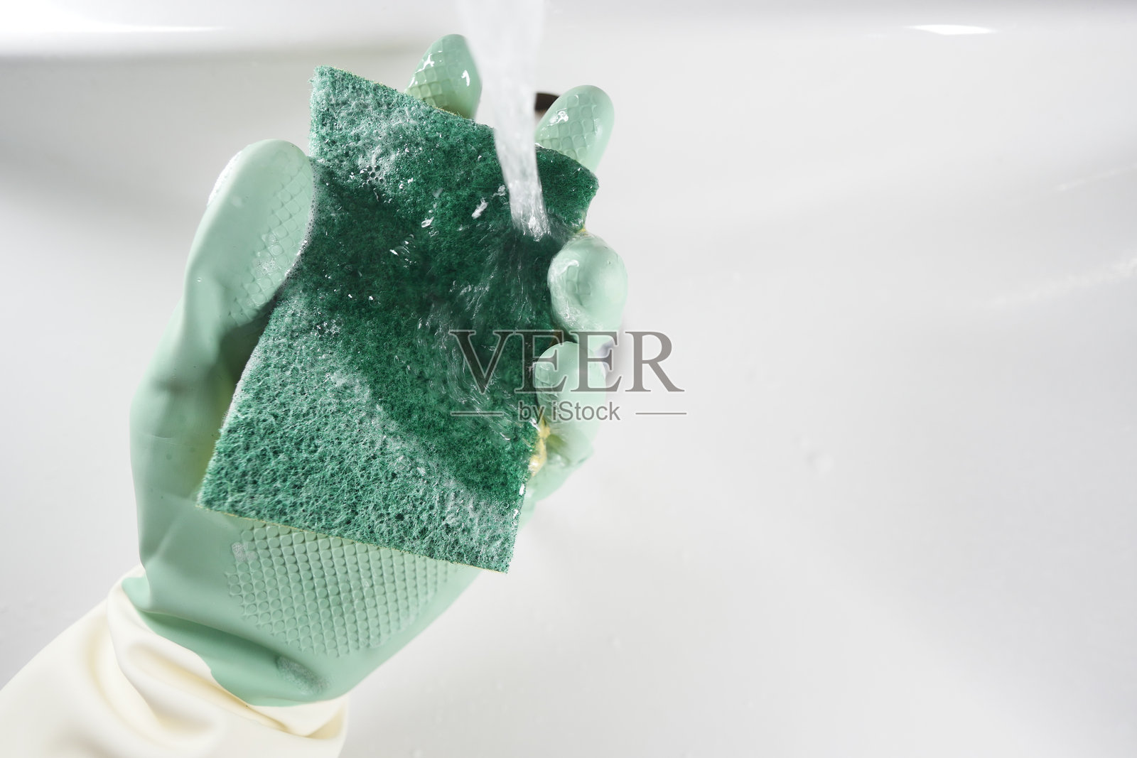 在厨房用流动水彻底清洗海绵以确保有效卫生照片摄影图片