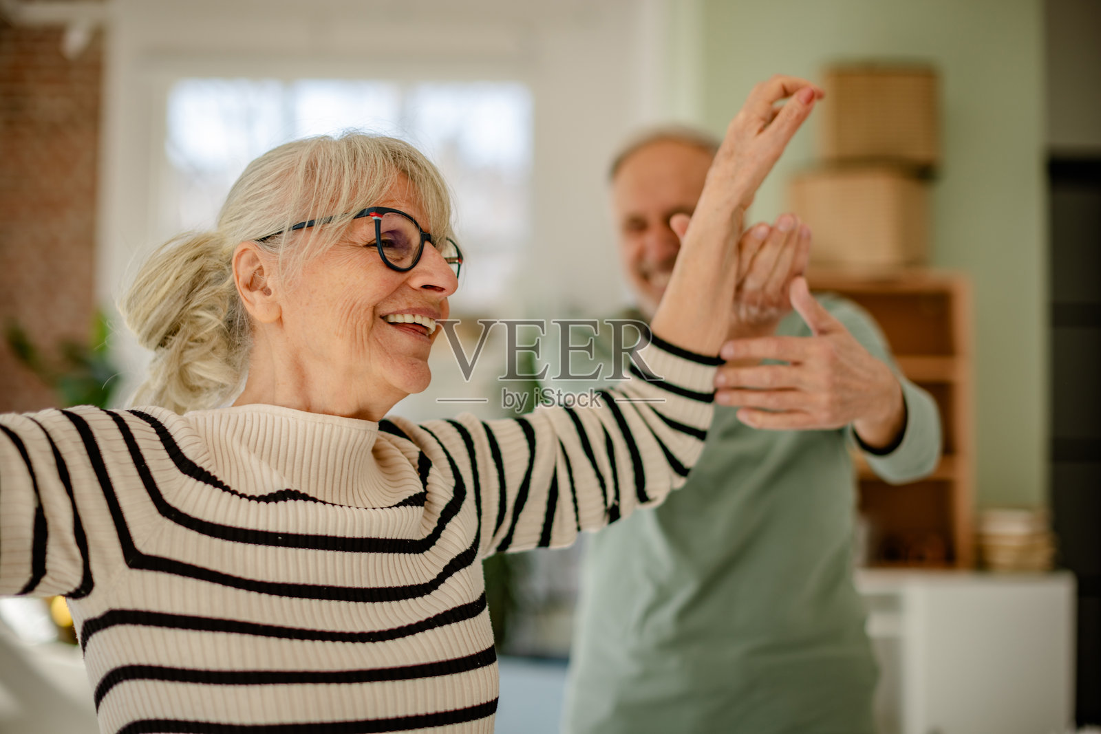 老年夫妇快乐地一起装饰他们的新家,享受着他们的黄金岁月。照片摄影图片