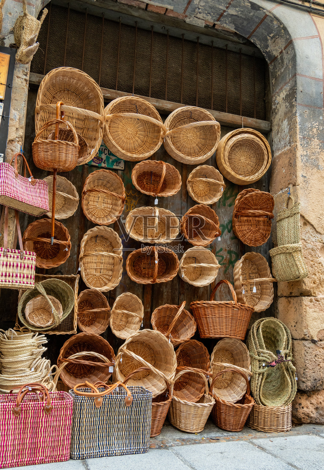 在历史悠久的小镇的鹅卵石街道上,一家迷人的手工艺品店外展示着精美手工编织的篮子。照片摄影图片