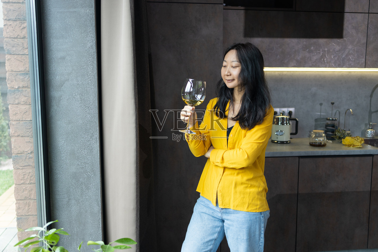 年轻亚洲女性在厨房窗边喝酒照片摄影图片