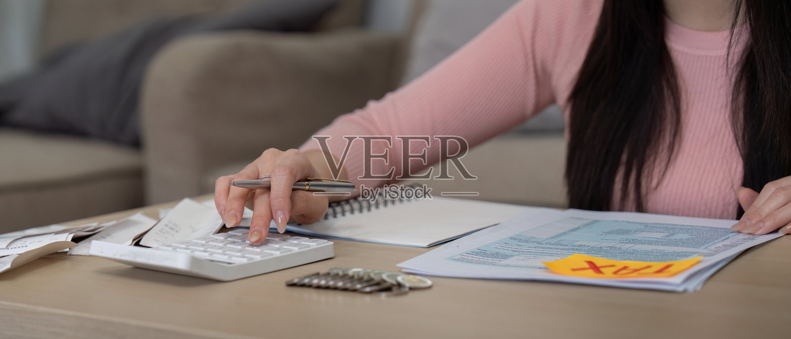 女性在家中使用计算器和财务文件计算税款照片摄影图片