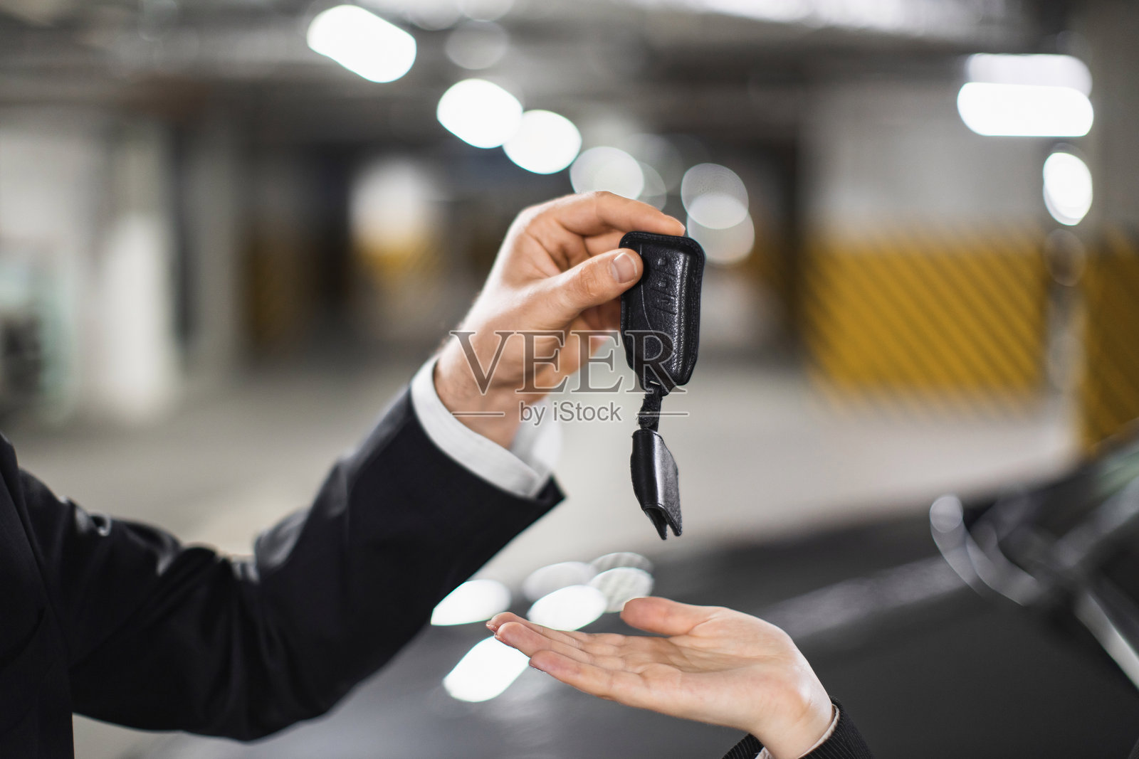 白人商人在停车场将车钥匙递给一位女性照片摄影图片