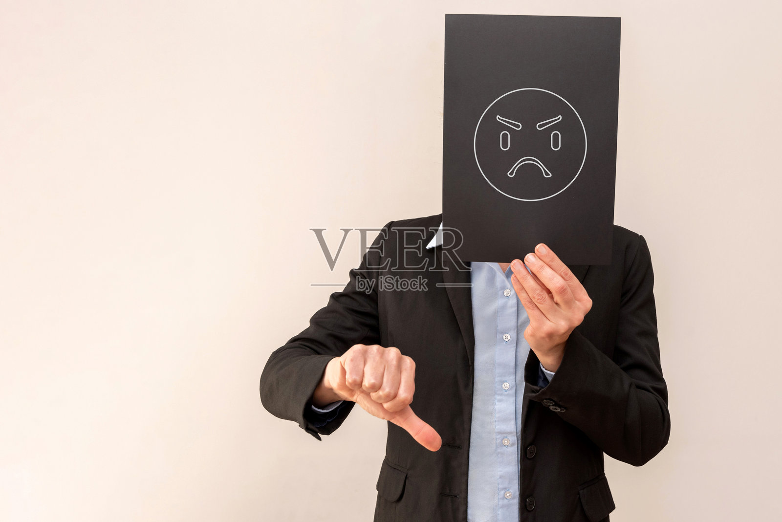 商人用愤怒的表情符号遮住脸并竖起大拇指向下照片摄影图片