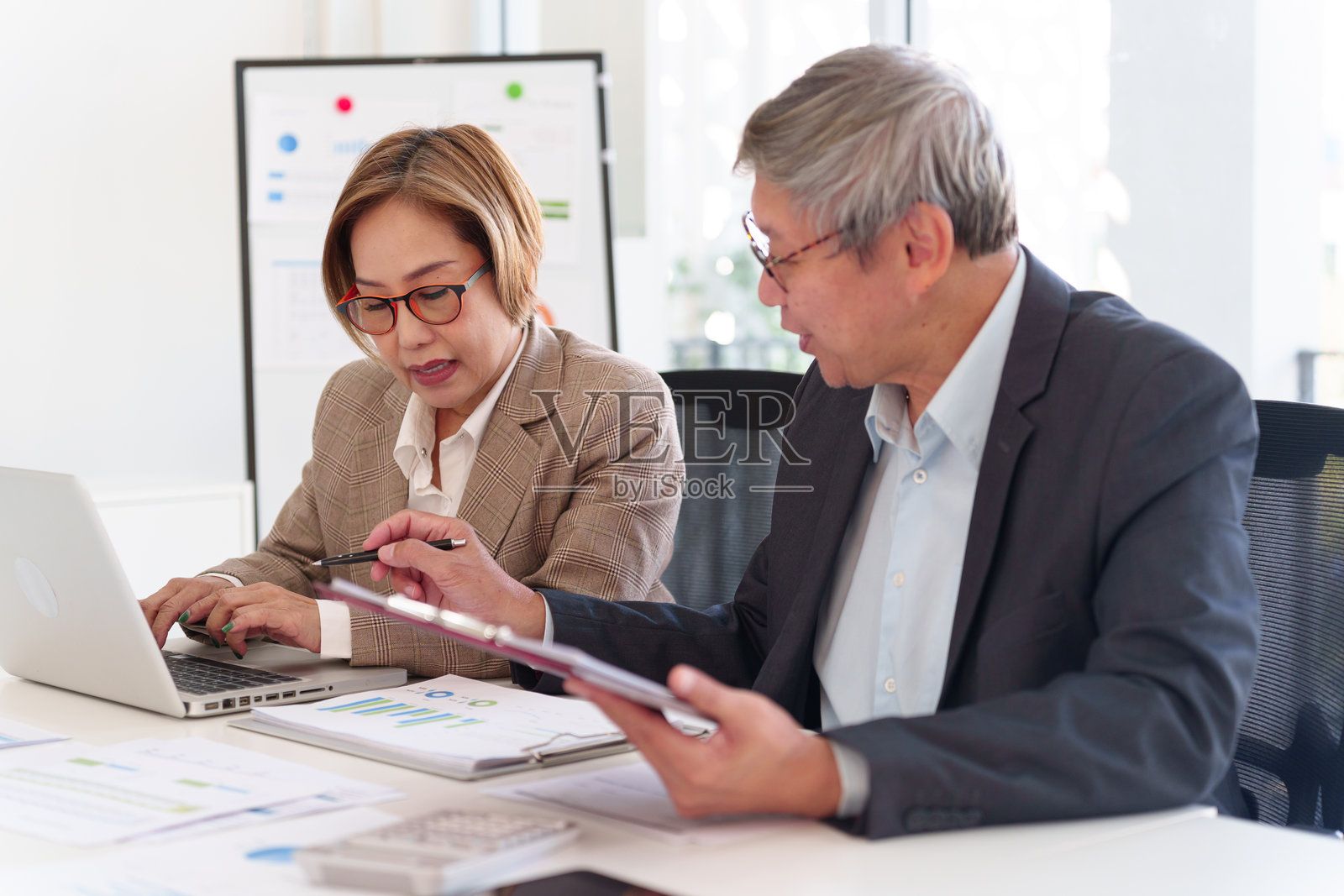 资深商业专业人士在现代办公室中共同分析财务数据,审阅报告并讨论投资策略。照片摄影图片