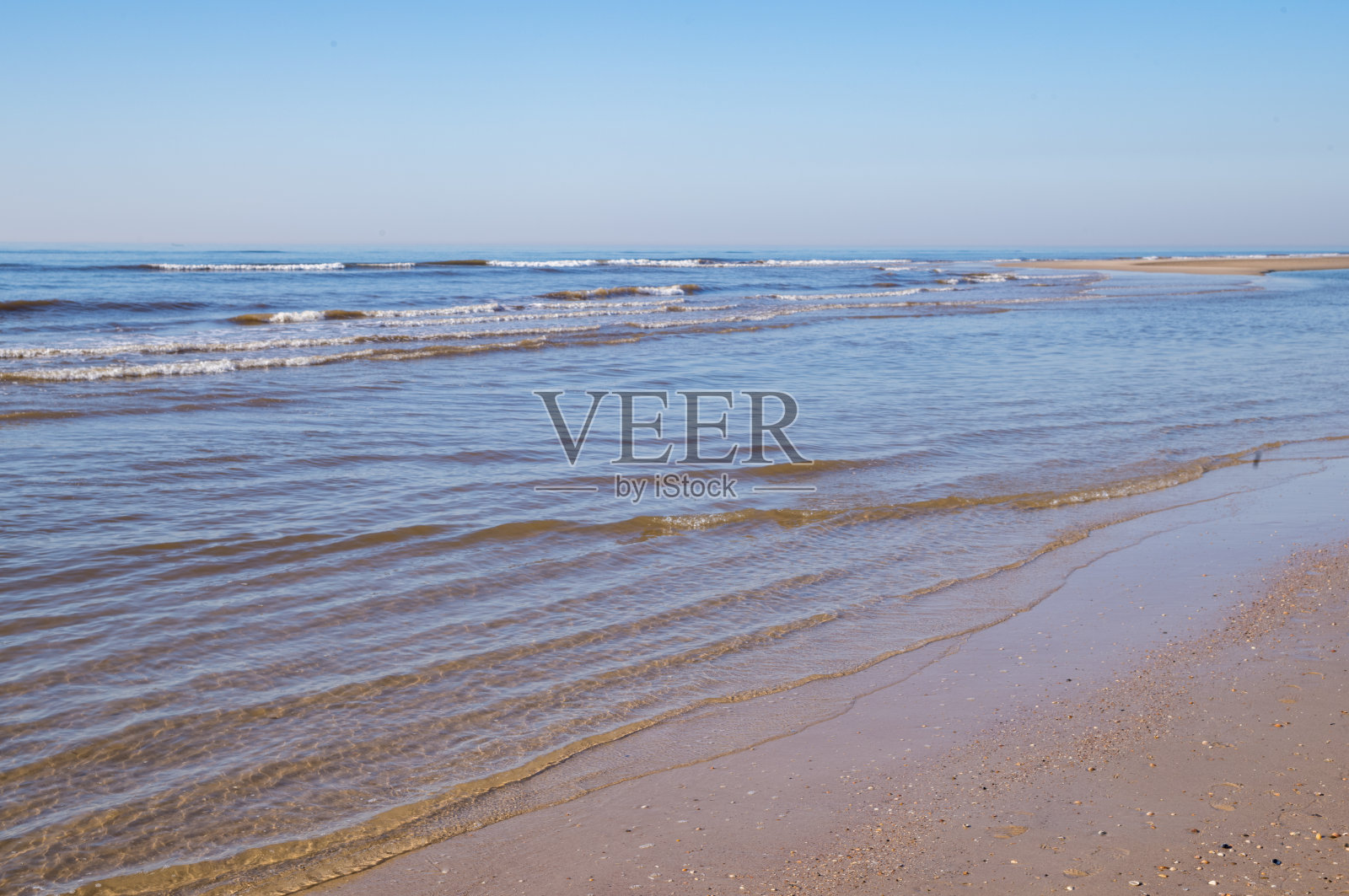 温暖阳光下,温柔的海浪拍打着沙滩照片摄影图片