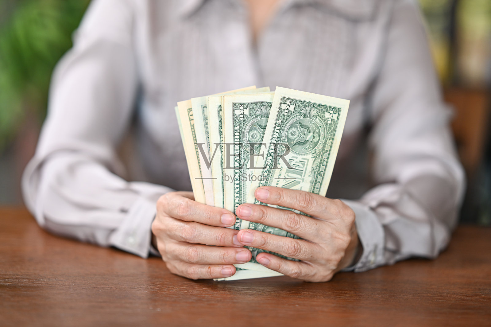 手中握着美元钞票。个人贷款、家庭财务、收入、储蓄的概念。照片摄影图片