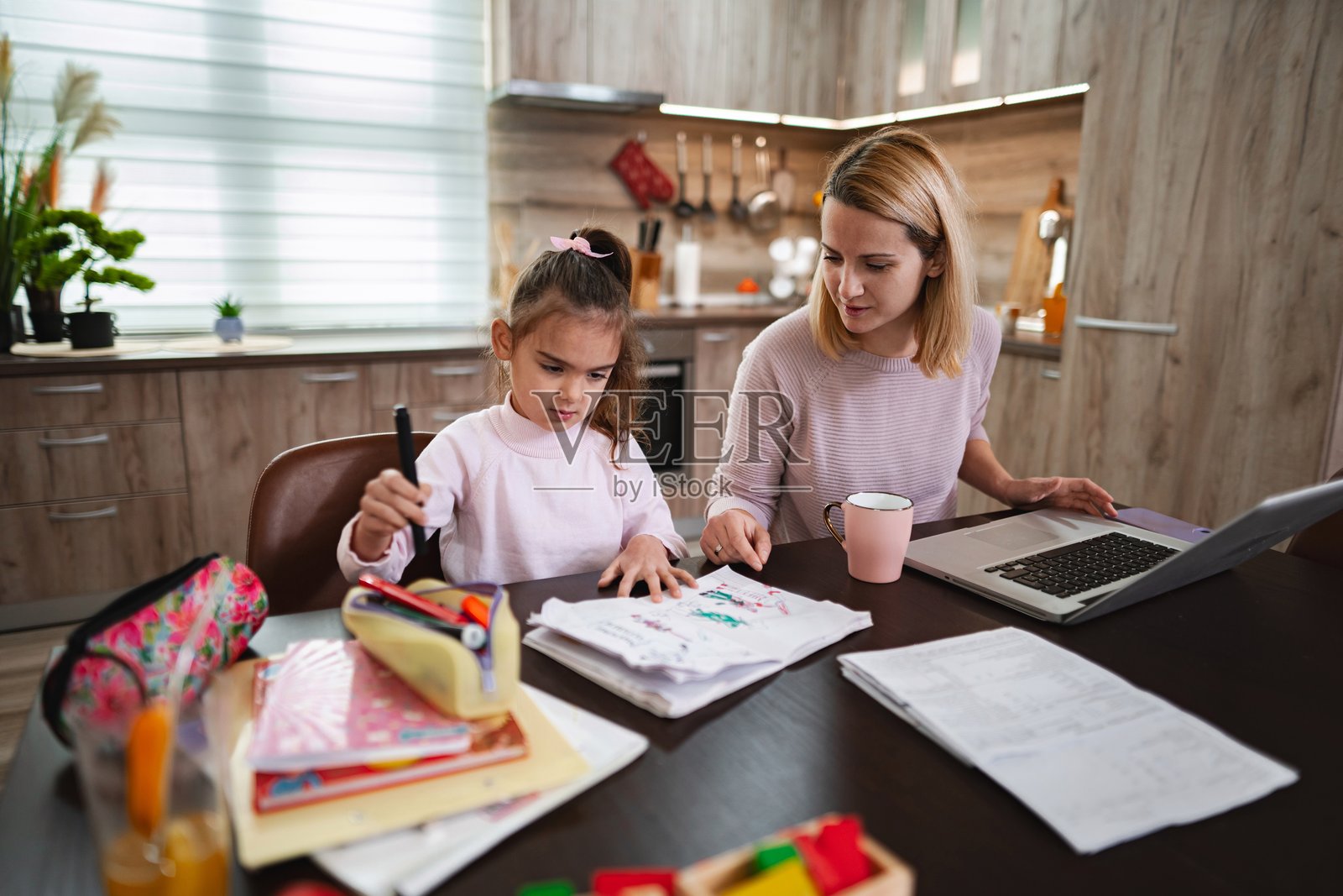 母亲在家工作时帮助女儿做作业照片摄影图片