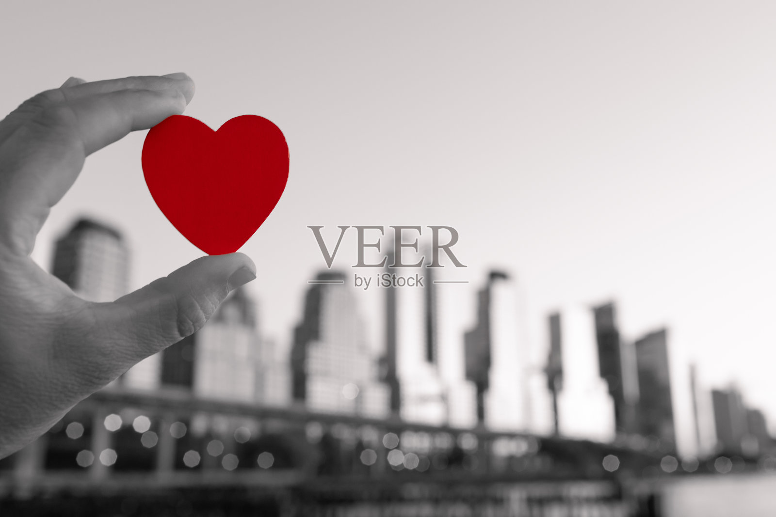 手握心形图案,背景是纽约市,展现爱心、慈善支持和同情。城市中的情人节。照片摄影图片