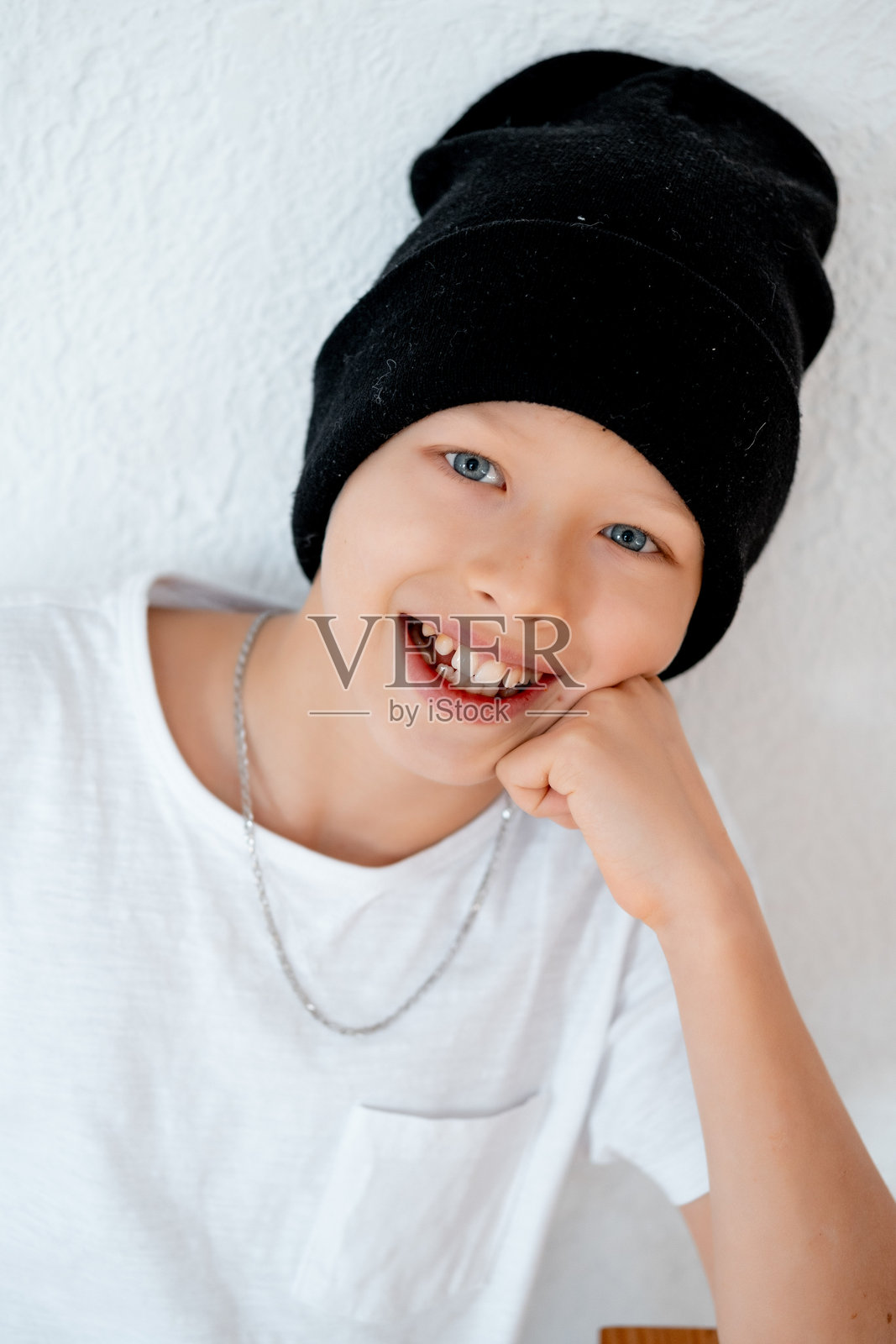 青少年男孩特写肖像,白色背景下穿着黑白衣服的男孩戴着帽子。照片摄影图片