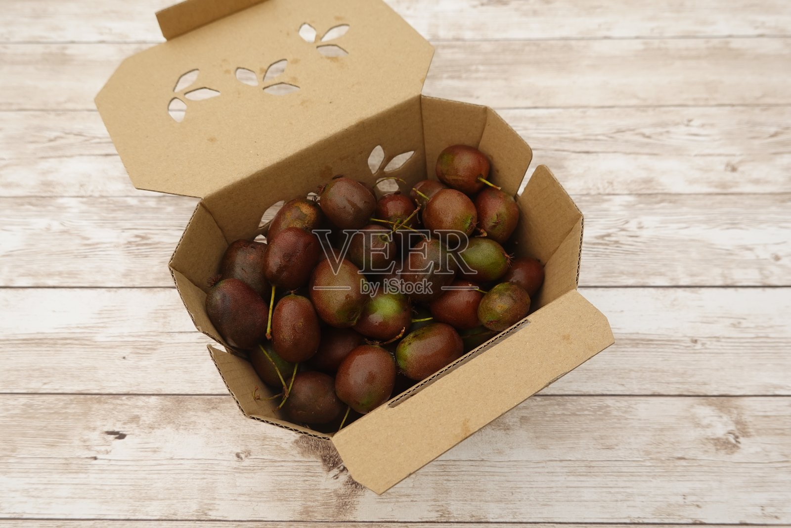 装满新鲜采摘的猕猴桃浆果的纸箱,放在乡村风格的木桌上照片摄影图片