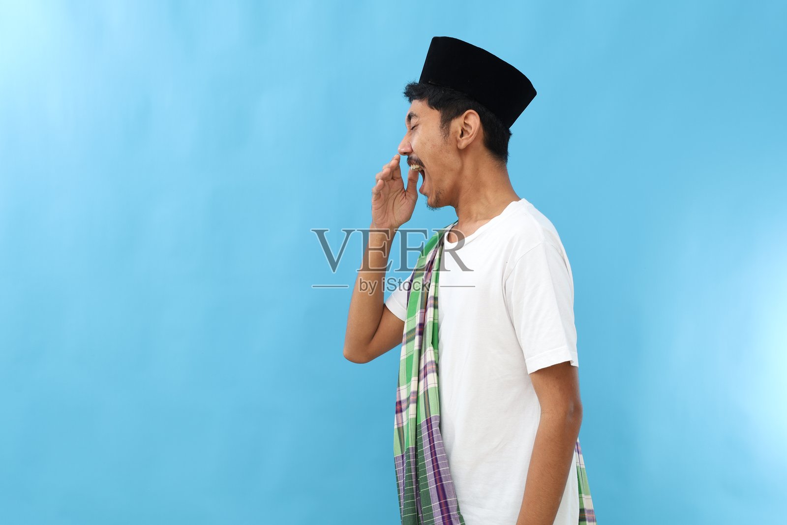 在蓝色背景下,正在斋月期间面临口臭问题的亚洲穆斯林男子照片摄影图片
