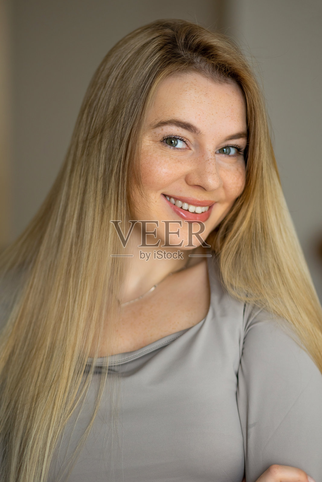 微笑的金发长发女性在休闲的室内环境中摆姿势照片摄影图片