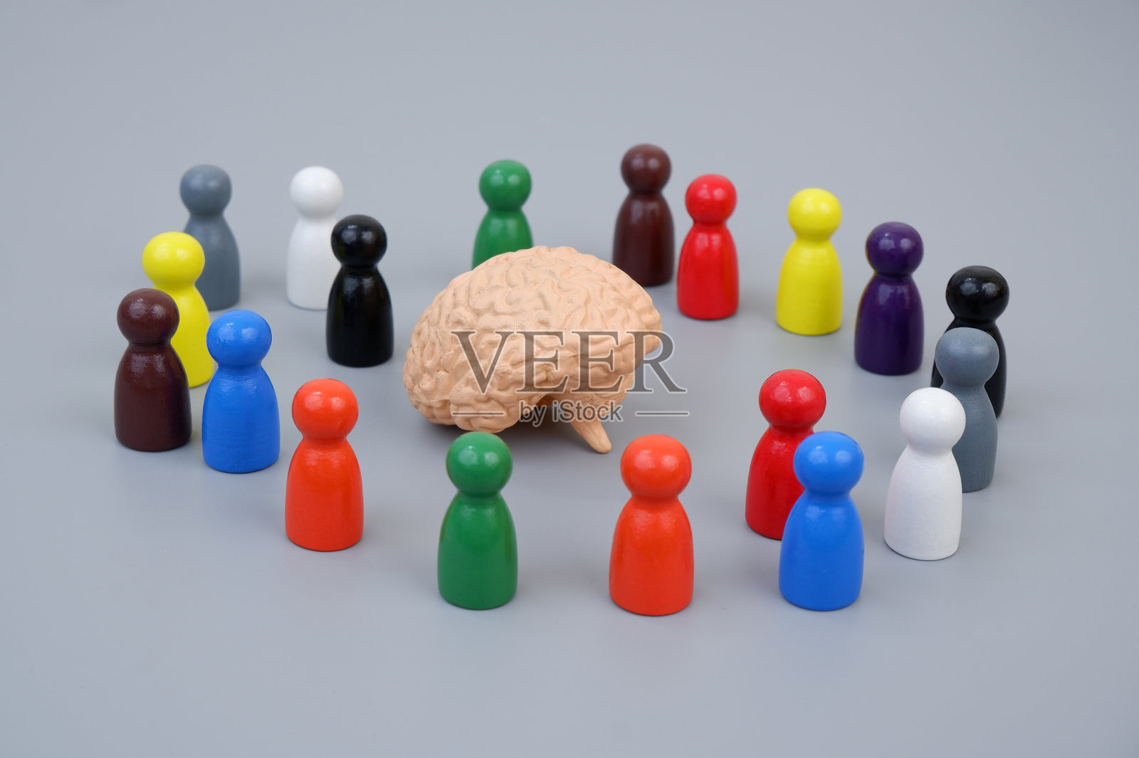 灰色背景上围绕着大脑模型的木质人形玩偶。照片摄影图片