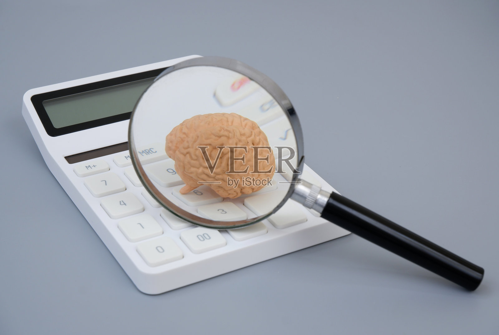 放大镜下的计算器上的人脑模型。照片摄影图片