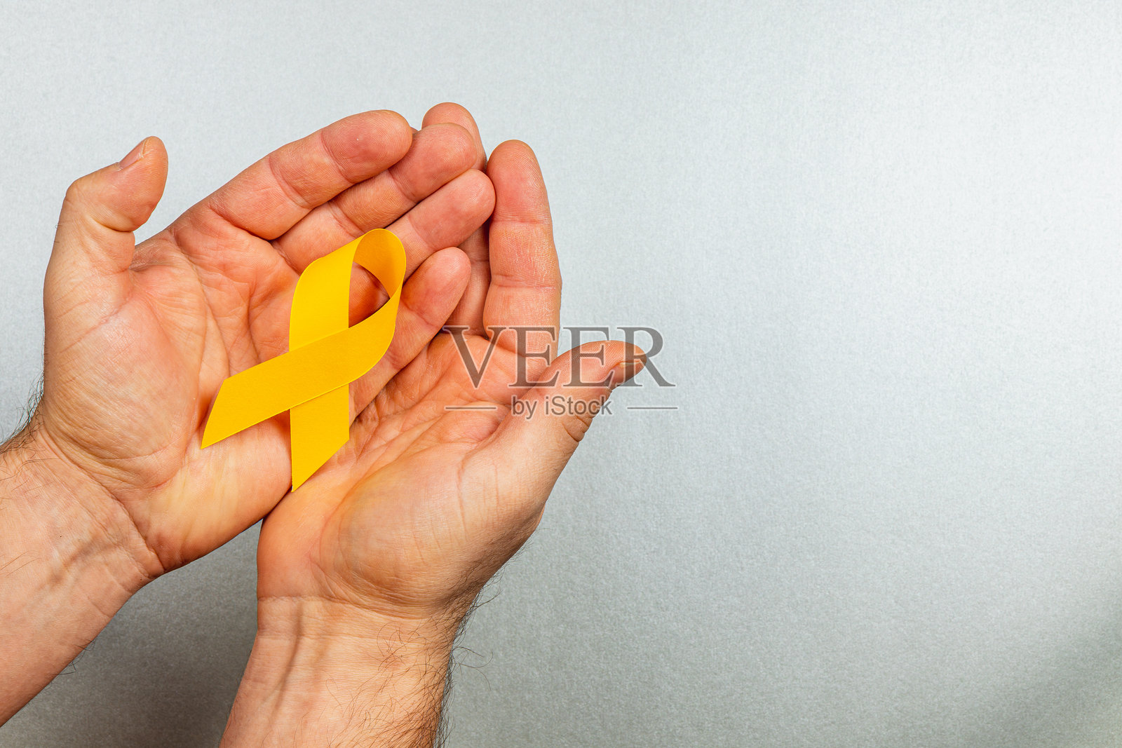 手中握着象征癌症意识的黄色丝带照片摄影图片