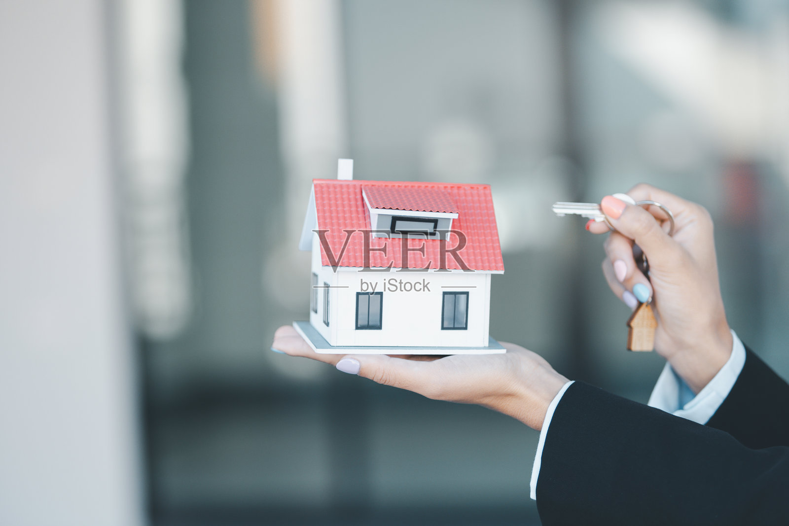 女性手握钥匙,购买房屋模型,商业概念涉及销售、财务管理、投资银行贷款、所有权、收入、经济、金融投资和公寓购买,背景模糊的房地产。照片摄影图片