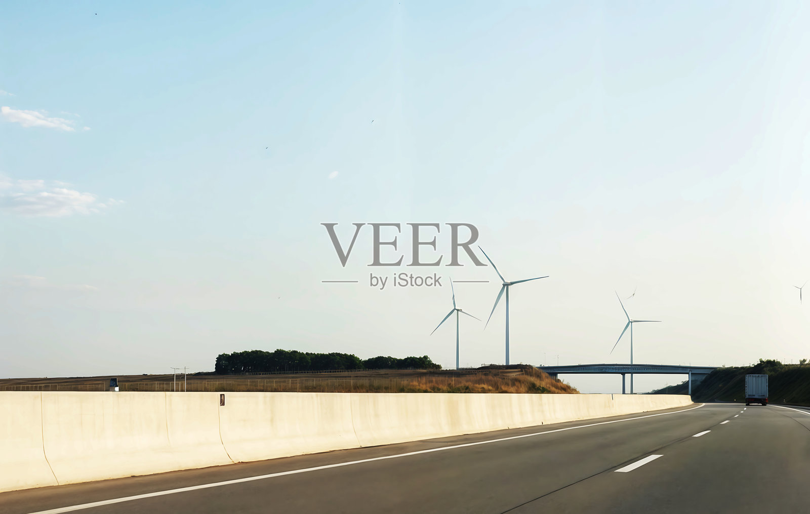 现代风景中有风力涡轮机,沿着道路而建。高大的白色结构在风的影响下旋转。照片摄影图片