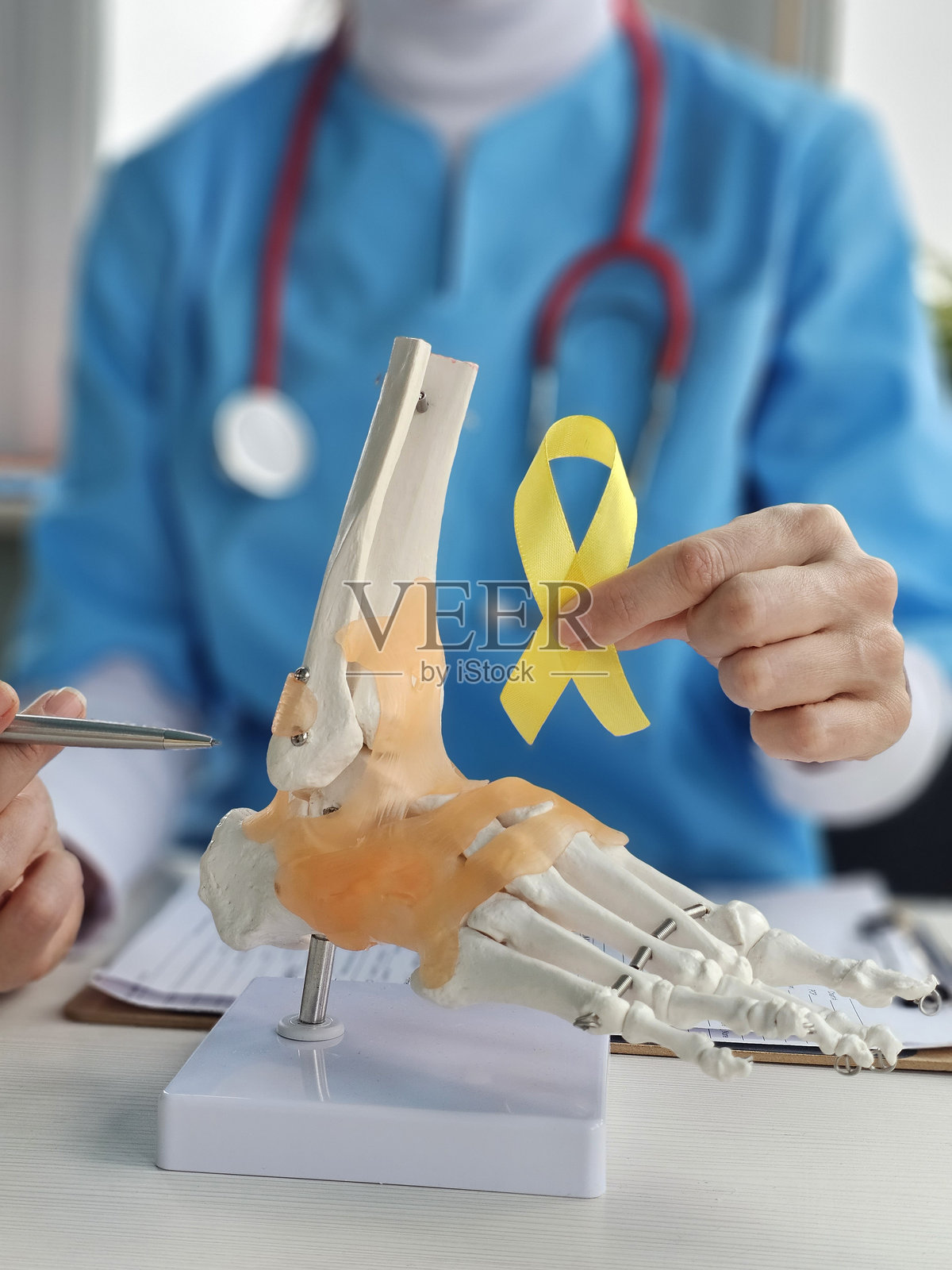 医生在讨论脚部解剖模型,同时手持黄色意识丝带照片摄影图片