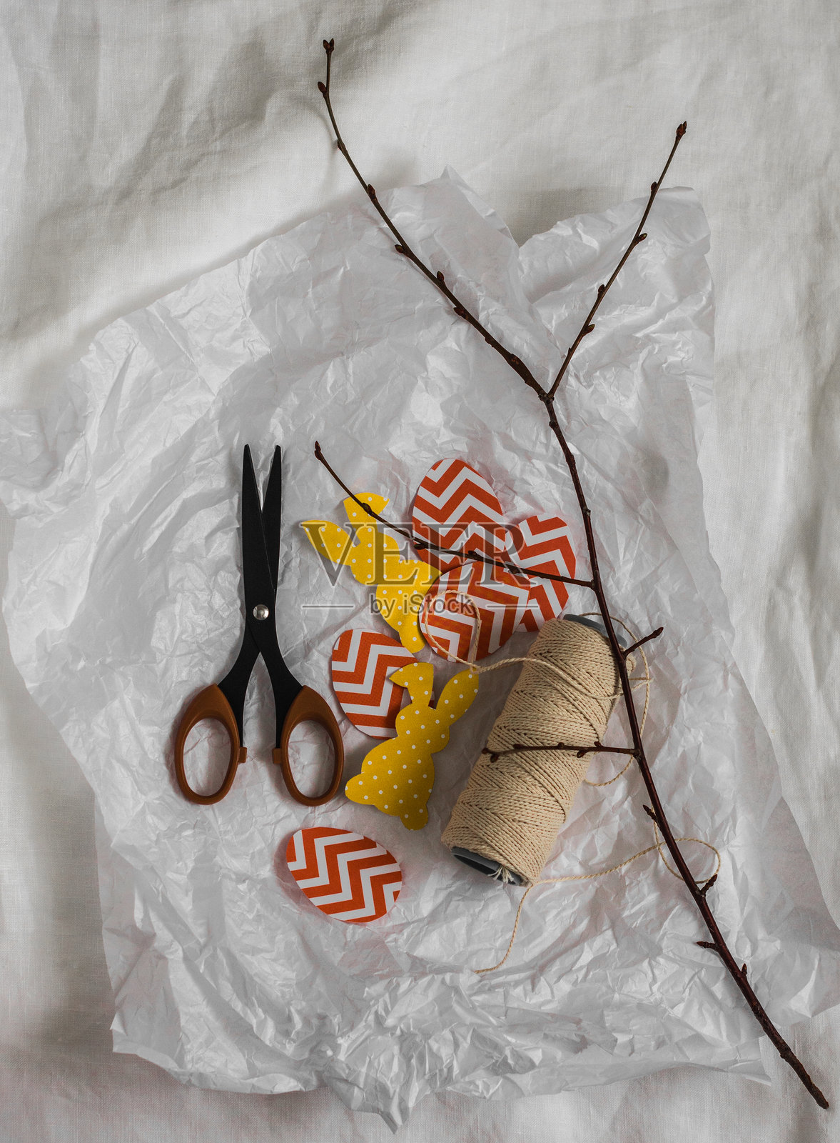 制作复活节花环的细节 - 纸兔子、彩蛋、剪刀、麻绳,浅色背景,俯视图照片摄影图片