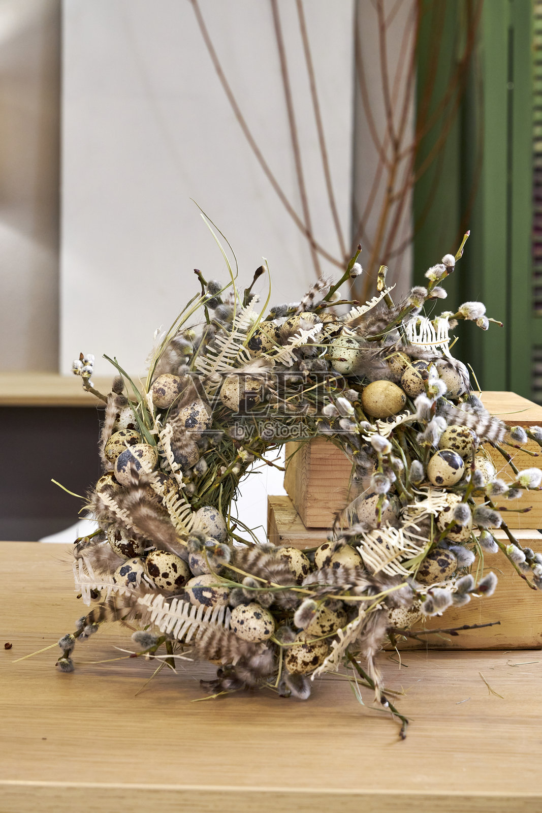手工制作的柳树和鹌鹑蛋复活节花环靠在室内白色墙壁上照片摄影图片