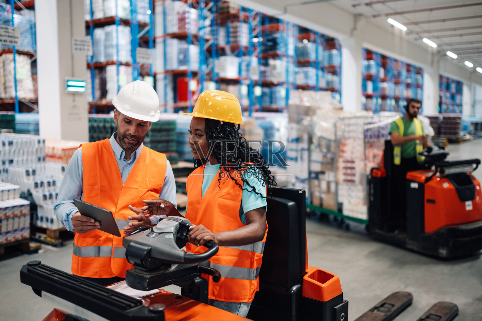 仓库工人在物流中心使用平板电脑和驾驶叉车照片摄影图片