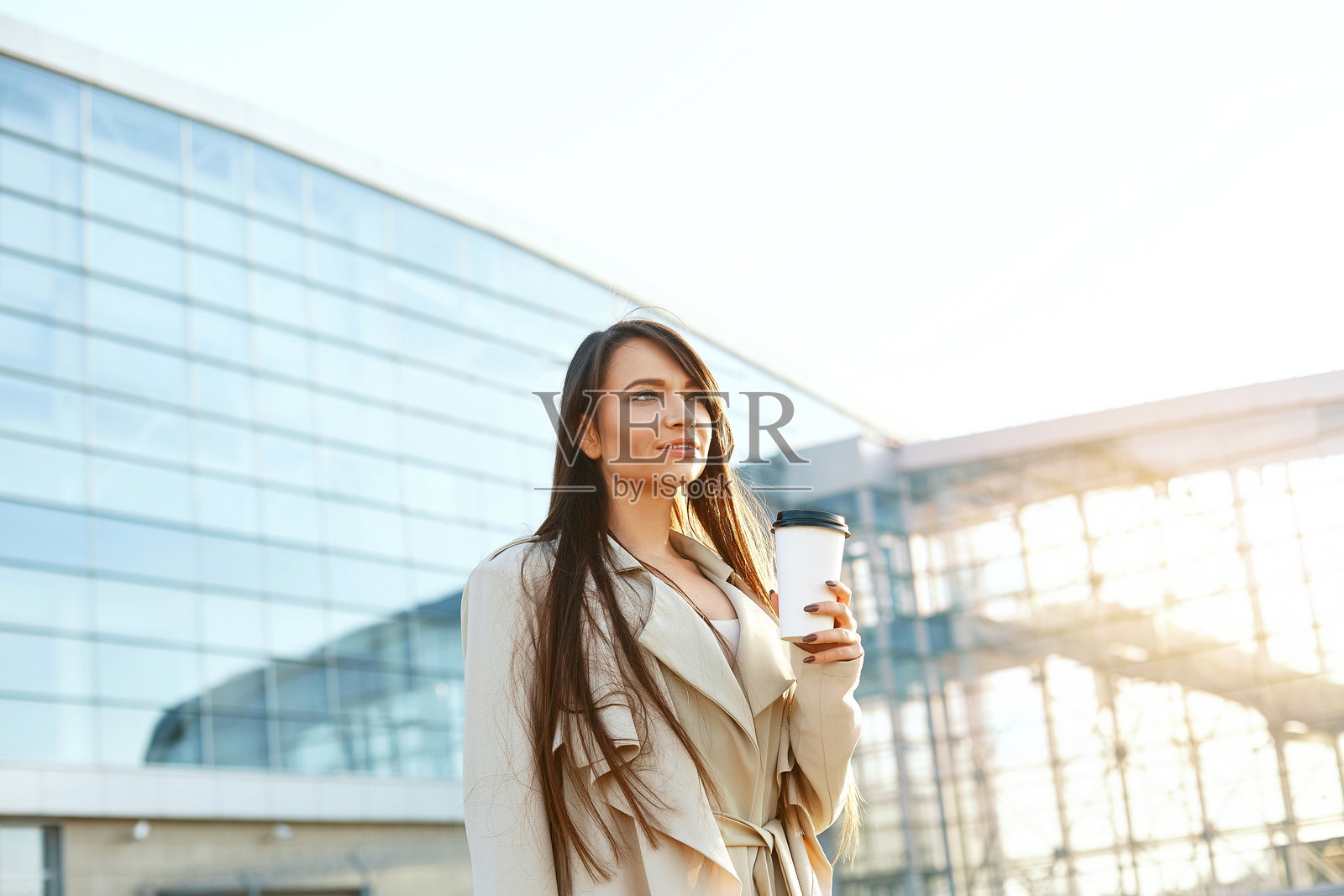 商务女性在办公室附近手持咖啡杯。美丽微笑的女性肖像,站在户外。照片摄影图片