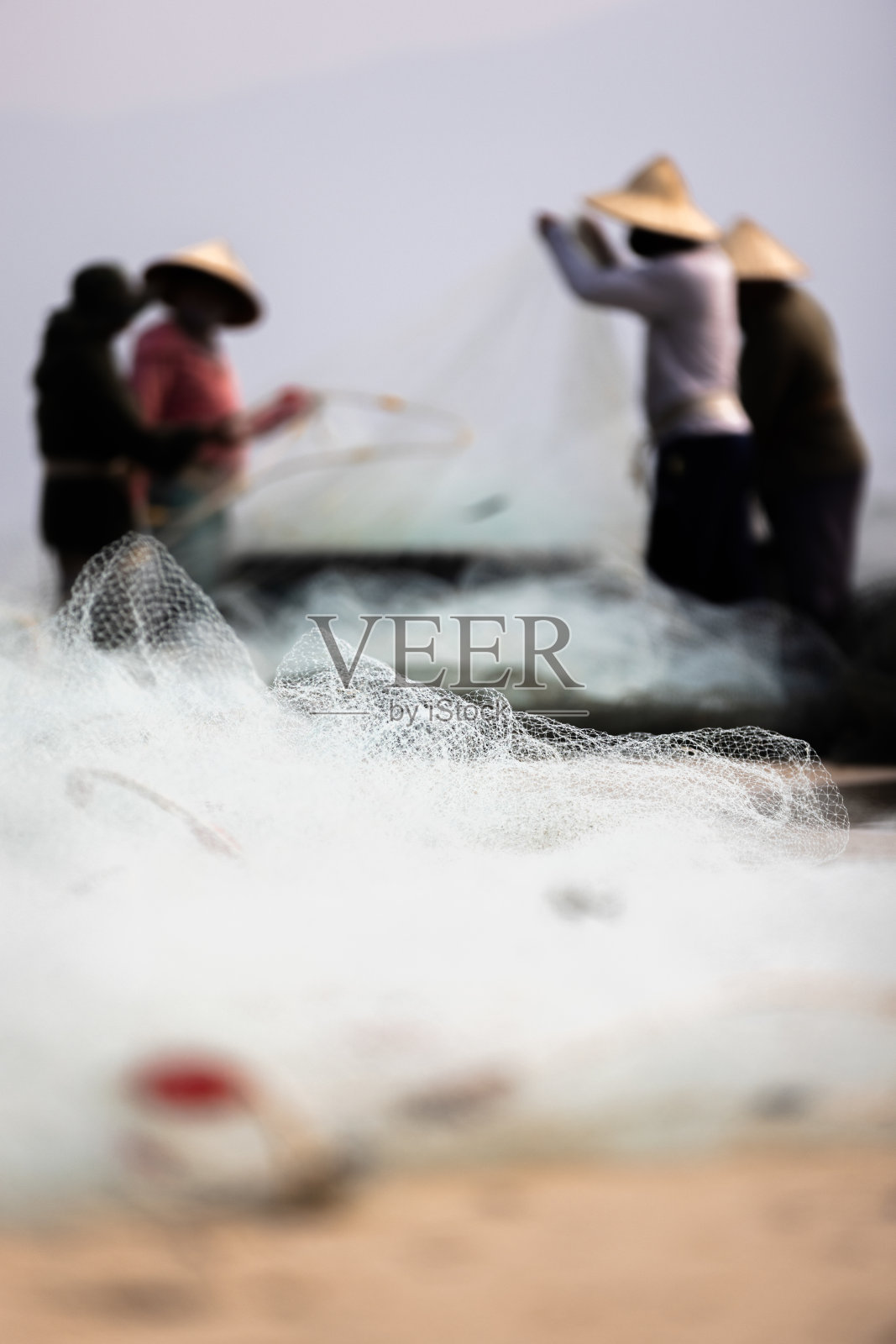 一群越南渔民正在用渔网捕捞鱼。照片摄影图片