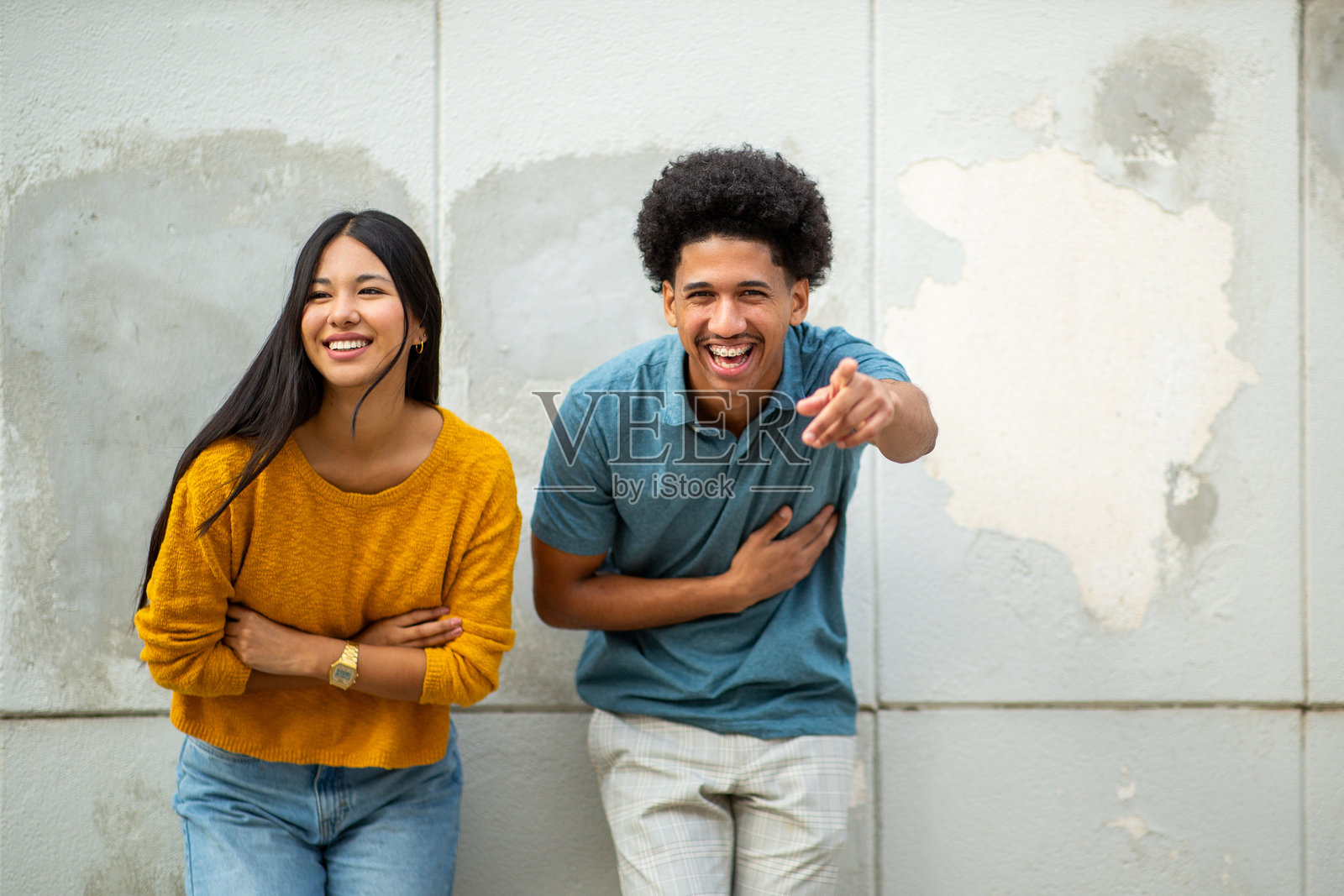 快乐的年轻情侣在墙边欢笑照片摄影图片